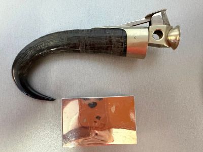 a metal object with a black handle on a white surface