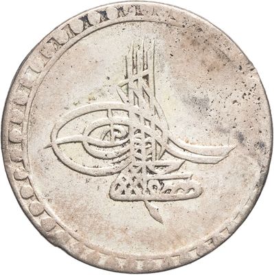 Gros plan sur une pièce de monnaie en argent portant une inscription en arabe