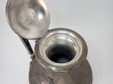 a silver vase with a lid on a white table