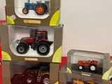 four toy tractors in boxes on a red table