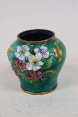 un vase avec des fleurs peintes dessus, posé sur une table