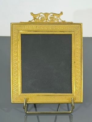un cadre doré avec un tableau noir posé sur un support