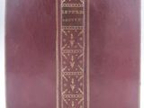 un vieux livre à la couverture rouge posé sur une surface blanche