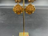 a close up of a pair of gold earrings on a stand