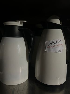 two white and black coffee kettles sitting on a counter