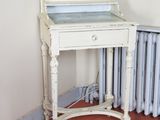 un bureau blanc sur lequel est posé un miroir, dans une pièce équipée d'un radiateur