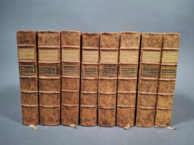 six vieux livres sont alignés sur une surface grise