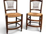 two wooden chairs with wicker seats on wheels against a white background