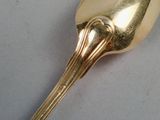a gold spoon with a spoon handle on a white surface