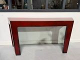 une table rouge avec un plateau en verre, placée devant une fenêtre