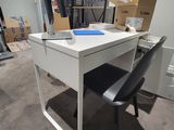 un bureau blanc avec une chaise noire dans une pièce