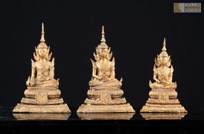 trois statues en or représentant des bouddhas assis sur un socle noir