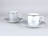 deux tasses et soucoupes aux bords argentés sont posées sur une table