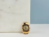 a small gold watch sitting on a marble block