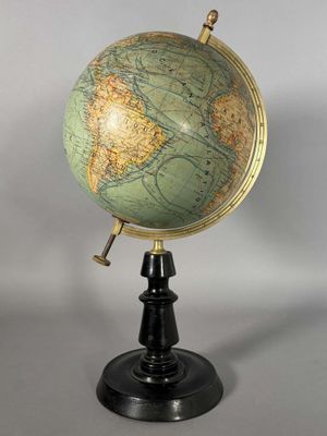 un globe vert et or posé sur un socle noir, sur fond blanc