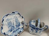 a blue and white plate with a cup and saucer and a plate with a boat on it