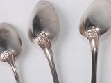 three silver spoons sitting next to each other on a white surface
