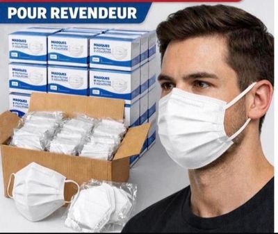 un homme vêtu d'un t-shirt noir et portant un masque blanc, à côté d'une boîte de masques