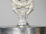 a silver vase with a silver emblem on top of it