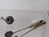 a glass display case with a pair of tonges and a pair of earrings