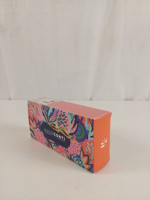 une boîte rose ornée d'un motif floral, posée sur une surface blanche