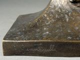 bronze statue of a dog on a pedestal with a name engraved on the base