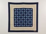 un foulard carré à motifs cachemire bleus et blancs accroché à un mur blanc