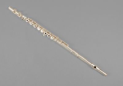 a silver flute with a flute stick on a grey background