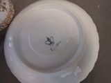 a white plate with a flowered design on it next to a vase