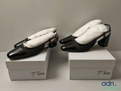 deux paires de chaussures noires et blanches posées sur des cartons