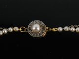 a close up of a bracelet with pearls on a black surface