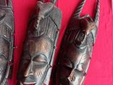 three wooden masks on a table with a red cloth