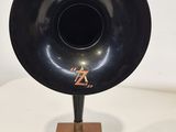 un gramophone noir posé sur un socle en bois, sur une table blanche