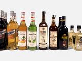 de nombreuses bouteilles d'alcool alignées sur une surface blanche