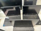 three laptops are sitting on a table with a keyboard and monitor