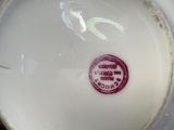 a close up of a white vase with a red sticker on it