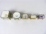 six pieces of porcelain boxes are lined up on a white surface