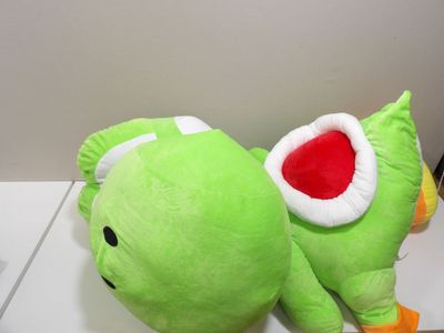 a green stuffed animal that is laying down on a table