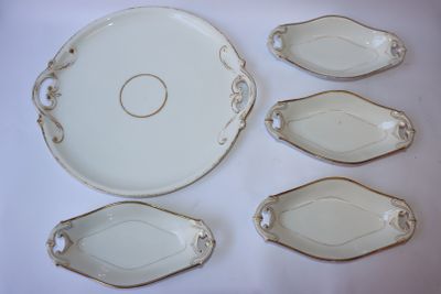plusieurs pièces de porcelaine blanche ornées de bordures dorées, disposées sur une table blanche