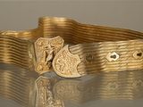 une image montrant un gros plan d'une ceinture dorée munie d'une boucle