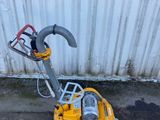 La petite machine jaune est posée sur le béton, près du mur.