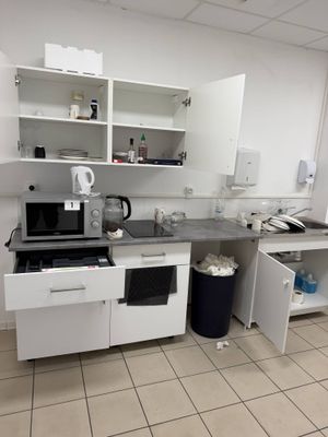 a kitchen with a sink, stove, microwave, and a trash can