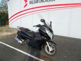 une moto noire garée sur un parking, près d'un mur