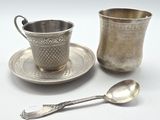 une tasse et une soucoupe en argent, avec une cuillère à côté