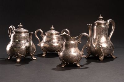 trois théières en argent et une cafetière sur une table