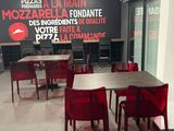 des tables et des chaises dans un restaurant où est accrochée une grande enseigne au mur