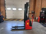 un chariot élévateur rouge dans un garage avec deux autres chariots élévateurs