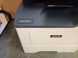 an xerox printer sitting on top of a desk next to a chair