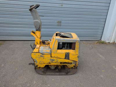 une photo d'une machine jaune garée devant un garage