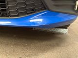 the front bumper of a blue car with a diamond plate on it